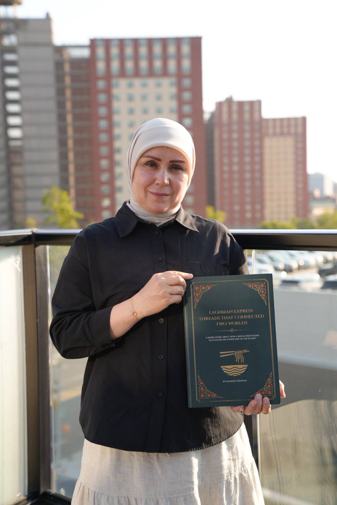 Author Gulnoza Jurayeva holding her Laghman Express publication